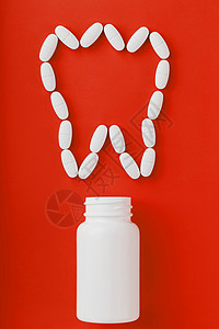 在红色背景上从白罐子里洒出一颗牙状的钙维他命矿物质疼痛疾病药品止痛药维生素处方医生制药抗生素图片