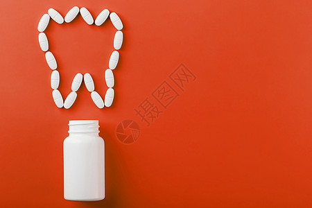 在红色背景上从白罐子里洒出一颗牙状的钙维他命抗生素健康银行丸药处方药店矿物质疼痛医生蓝色图片