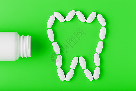 在绿色背景的白色罐子上洒出的牙齿 以维生素钙的形式呈现出来剂量丸药药丸药品银行抗抑郁药疾病化学品治疗蓝色图片