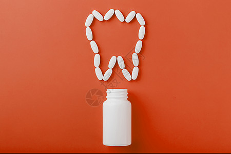 在红色背景上从白罐子里洒出一颗牙状的钙维他命蓝色抗生素处方制药胶囊药店医院银行医生疼痛图片