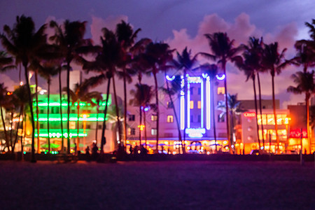 日落时迈阿密海滩海洋大道酒店和餐厅的模糊背景 晚上有棕榈树的城市天际线 南海滩的装饰艺术夜生活图片