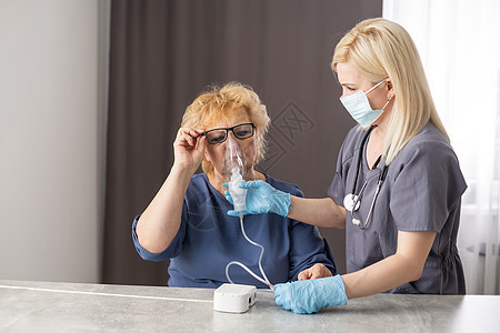 年轻女医生 持有氧气面具 超过老年女性患者的脸图片