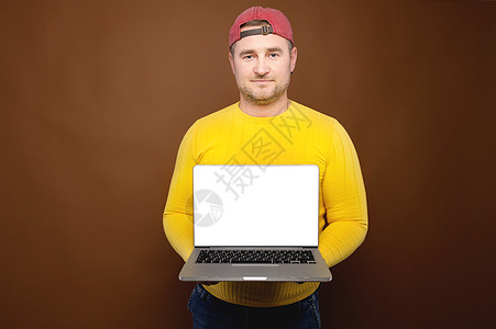 一名穿黄色毛衣和帽子 手持白剪切屏的露天笔记本电脑的随身画像工作室小人肖像 网站演示或应用程序复制空间图片