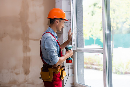 建筑施工现场窗户安装的男性工业建筑工人图片