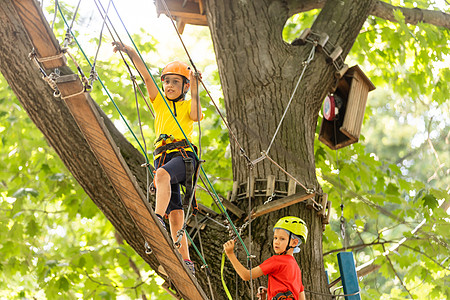 森林探险公园里的孩子 孩子们爬上高绳索道 敏捷和攀岩户外儿童游乐中心 在户外玩耍的小女孩 有索道的学校操场乐趣头盔闲暇公园滑索女图片