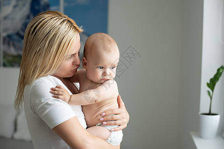 一位年轻的母亲抱着她刚出生的婴儿 哺乳婴儿的母亲 母亲母乳喂养她的孩子 家人在家 一个幸福的母亲和孩子的肖像拥抱喜悦女性儿子母性图片