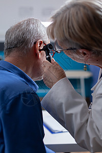 使用显眼镜对内阁内年长病人进行耳腔检查的近距离医疗医生图片