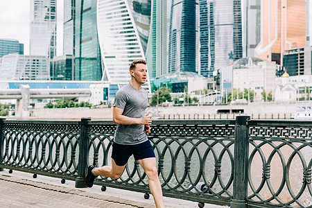 年轻的运动员男子赛跑者在夏天的早晨跑步 背景是城市街道 运动训练 在新鲜空气中进行健身有氧运动 在户外慢跑动机摩天大楼运动装身体背景图片