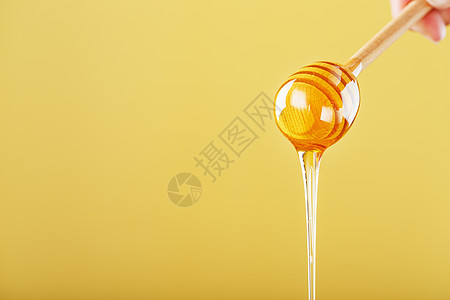 蜜糖从黄色背景的蜂蜜小溪流中滴落早餐味道勺子节食营养蜜蜂食物流动橙子细雨图片