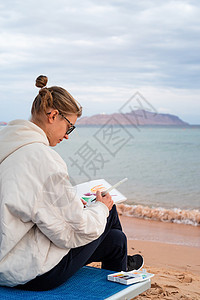 利用海边水彩色绘制或绘制旅行草图的年轻女青年艺术家绘画女士海滩工艺女性爱好闲暇刷子成人海滨水彩图片