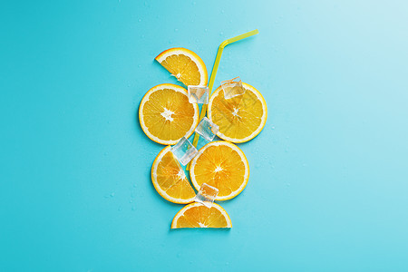橙色切片和冰块 以鸡尾酒的形状 在蓝色背景上的稻草饮料派对热带营养柠檬食物酒精液体水果果汁图片