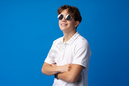 身戴眼镜和衬衫的少年男孩 蓝背景被孤立学生配饰青年休闲装男生教育乐趣快乐衣服孩子图片