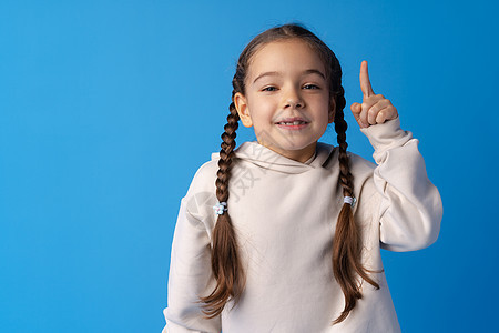 可爱的小女孩在蓝色背景下举起头来 有想法幼儿园童年手势学校孩子们幸福手指头脑快乐微笑图片