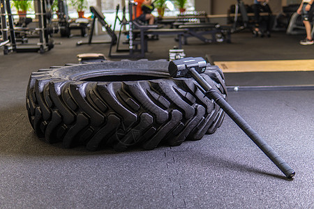 黑色背景上带有大锤的轮胎用于 crossfit 健身轮大锤锻炼体重 下午在生活方式集中锻炼 翻转俱乐部中锻炼力量 在室内大汗淋漓图片