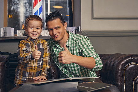年轻父亲和他时髦的小儿子 在候诊室理发店快乐发型孩子儿子皮椅客户童年头发成人男生图片