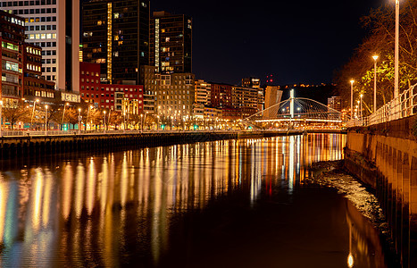 现代建筑的城市景观在河流和桥梁附近的夜晚 现代建筑办公楼 摩天大楼与街灯夜灯 商业和金融中心大楼图片