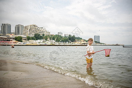 一个小男孩独自在低潮下探索海滩 走向海滨 快乐的童年概念 笑声钓鱼喜悦文化孩子海岸护腕蓝色旅行环境闲暇图片