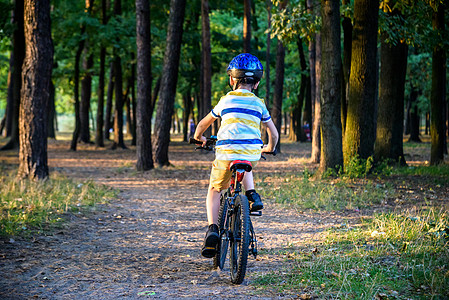阳光明媚的秋日 放学后在美丽的公园里骑自行车放松的戴着安全头盔的快乐活跃少年的画像孩子森林男生娱乐学校男性活动青少年晴天家庭背景图片