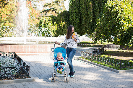 年轻母亲在公园里走路 推着婴儿车幸福闲暇女性妈妈家庭婴儿母性新生女士越野车图片