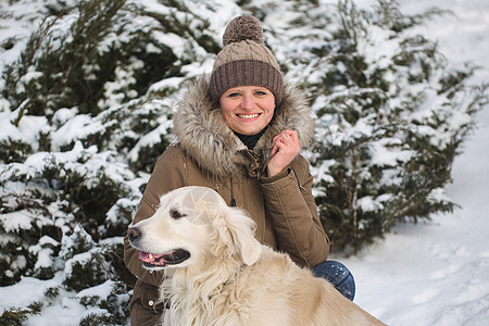 美丽的女孩在雪地里玩她的狗 金色寻宝游戏女士季节猎犬公园女性拥抱微笑乐趣靴子朋友图片
