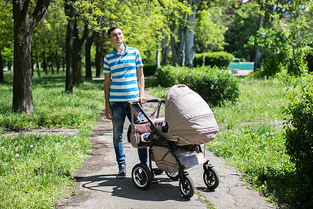 年轻人带着婴儿车在秋天公园走来走去图片