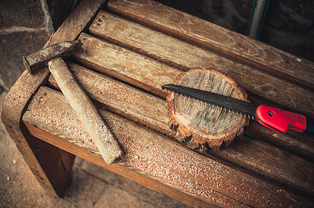 一个老锤子 一只手锯和一个长凳上有锯尘的松树圆棒 Wooden代表主班的食物 DIY概念手工具木工房子红色力量劳动锯末木头水平工背景图片