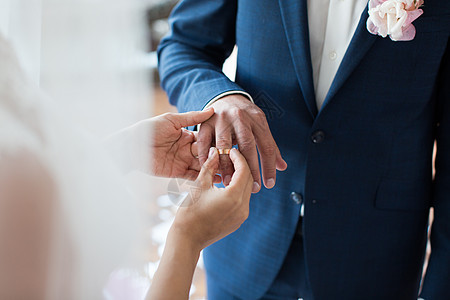 新娘在婚礼仪式上将戒指戴在新娘的手指上图片