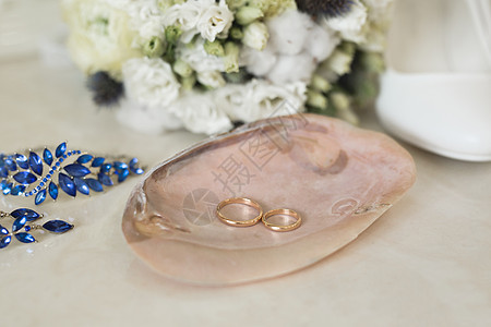 金婚戒贴在蓝色首饰和鲜花旁边的粉红色大理石贝壳上婚姻钻石婚礼背景惊喜广告新娘戒指仪式金属图片