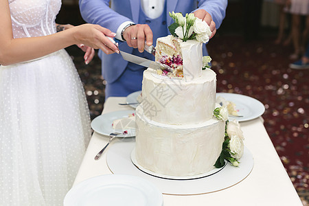 新娘和新郎在宴席上切了个漂亮的婚礼蛋糕套装传统婚姻丈夫夫妻派对甜点桌子盘子妻子背景图片