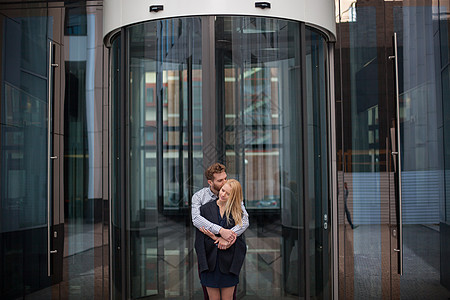 一个男人拥抱一个女人 在玻璃楼的幕后女郎建筑学女孩男朋友浪漫人士女郎乐趣城市跑步商业图片