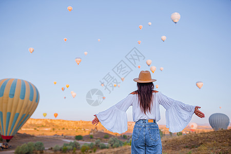 在土耳其卡帕多西亚观看热气球的日出快乐妇女岩石蓝色飞机吸引力工作悬崖女士胡同女孩日落图片