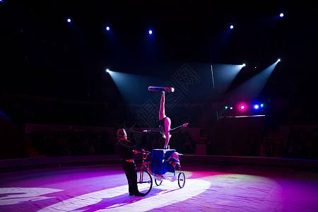 在马戏团圆顶下骑自行车的杂耍家剧院男人姿势艺术女孩体操空气空中飞人演员娱乐图片