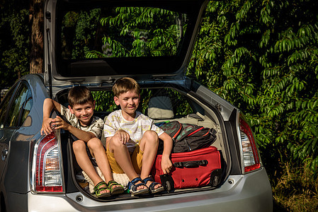 两个可爱的男孩在和父母去度假之前坐在汽车后备箱里 两个孩子期待公路旅行或旅行 在学校放暑假 家庭自驾游友谊车辆孩子们玩具树干行李图片