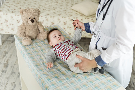 一个儿科医生在床上检查一个婴儿图片