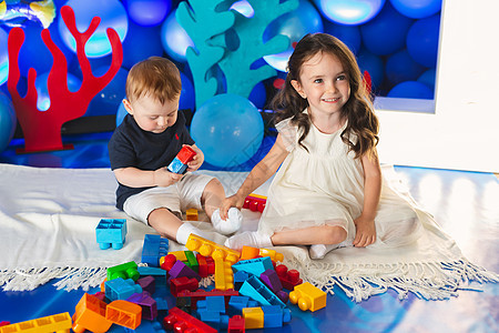 两个孩子 一个男孩和一个女孩 坐在房间里的地板上 笑着玩耍活动闲暇游戏室教育婴儿塑料创造力女孩孩子们幼儿园图片
