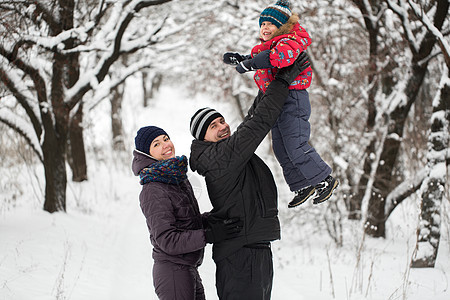 一个有孩子的年轻家庭 在一片雪覆盖的森林中走过儿子压痛森林季节青年喜悦男性父母父亲微笑图片