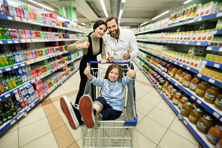 美丽的年轻父母和可爱的小女儿在超市中选择食物时笑着笑着微笑呢图片