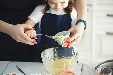 厨房里的年轻母亲和女儿 把蛋糕的面粉倒进模具里 手拉紧图片