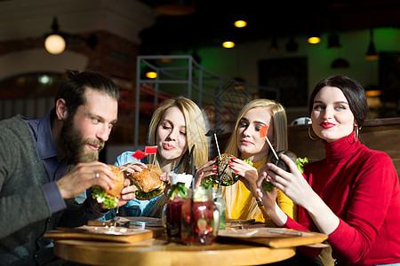 大家在咖啡馆的餐桌上共进晚餐 朋友吃汉堡和喝鸡尾酒快乐 在餐厅里派对友谊团体男人男性酒精成人女孩女性会议图片