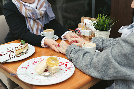 特写镜头的母亲和女儿的手在咖啡馆的木桌上 成年母女牵手喝咖啡妈妈女性女士微笑蛋糕女孩咖啡店桌子家庭咖啡图片