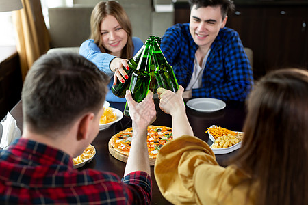 一群年轻朋友带着披萨和啤酒瓶在咖啡馆庆祝派对团体庆典长椅快乐瓶子桌子乐趣夫妻餐厅图片