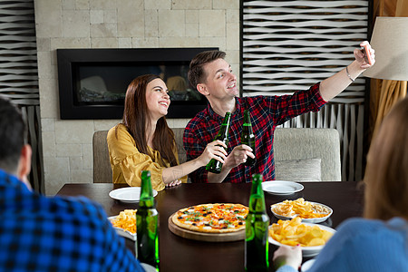 朋友喝啤酒 吃披萨 聊天和笑笑 在酒吧背景的智能手机相机上拍摄自拍友谊玻璃女士午餐男性团体咖啡派对女性技术图片