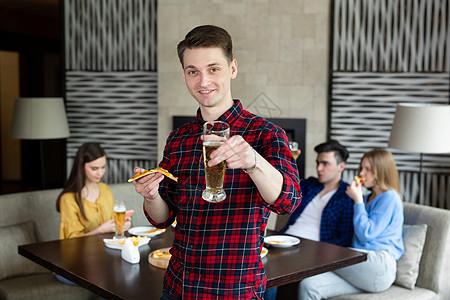 一个年轻人在酒吧里 拿着披萨和啤酒的肖像男人团体友谊乐趣女性闲暇快乐城市饮料咖啡店图片