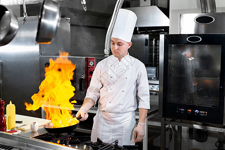 厨师在厨房炉子上用火烧锅煮饭烹饪酒店职业蔬菜美食平底锅餐厅男性烧伤用餐背景图片
