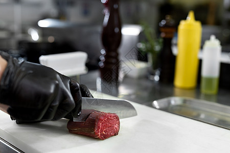 大厨在酒店或餐厅厨房做饭 只有手 他正在切肉或牛排图片