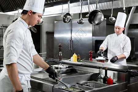 现代厨房 厨师在餐馆或旅馆厨房的炉灶上做碗盘燃烧帽子职业食物美食油炸蔬菜工作餐厅炊具图片