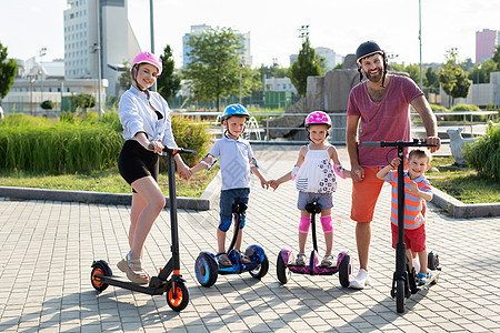 夏天在公园的电动小摩托车和Gyro小摩托车上 有小孩的家庭肖像图片