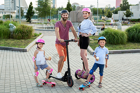 家庭快乐 孩子骑在Segways 电动摩托车和滑板上 夏季公园的小孩们玩得开心 孩子们吃冰淇淋图片