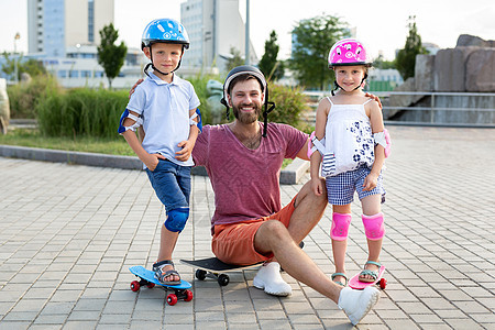 父亲和他的孩子 儿子和女儿 在公园滑冰 笑着看镜头图片