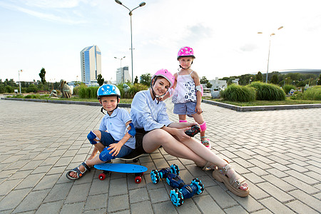 一位戴着头盔的孩子坐在滑板上 在公园里玩着一辆由手套控制的机器人车乐趣男生兄弟滑冰父母时间女士娱乐姐姐电子图片